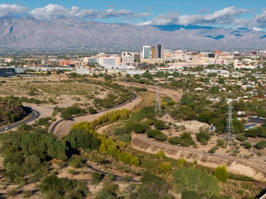 view from above of the Santa Cruz River Heritage Area with tall buildings of downtown Tucson in the background