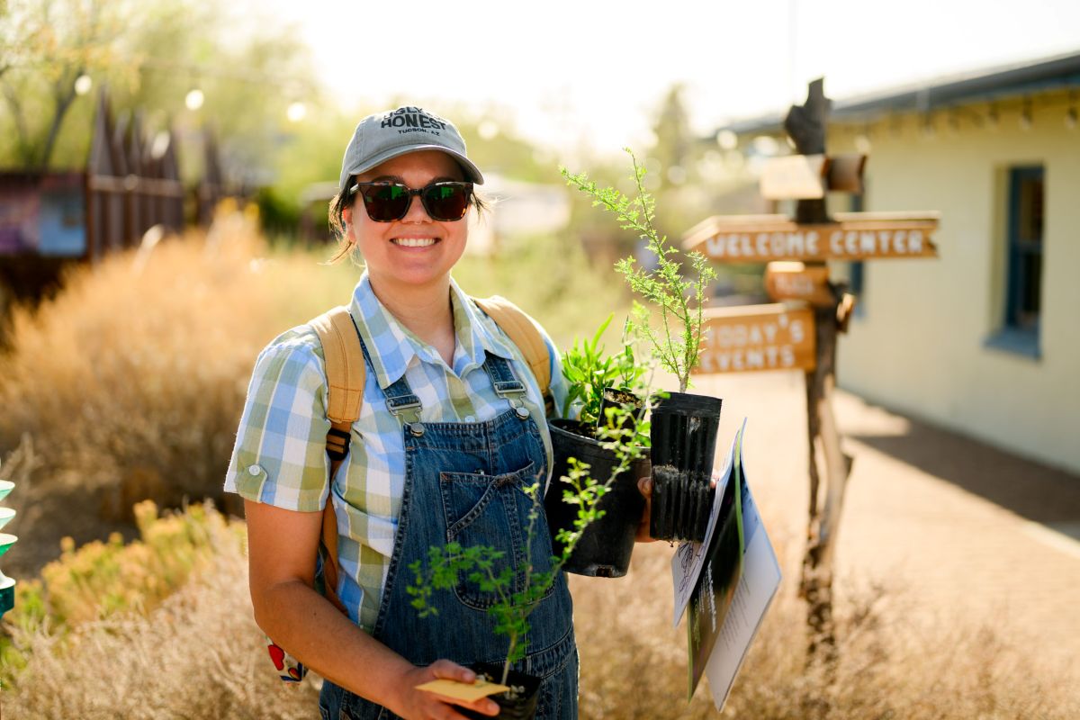 A Cool Tucson workshop participant holding her free kit of several native saplings