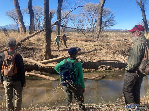 a group of people stand in front of a creek