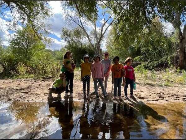 A group of children stand by a creek 
