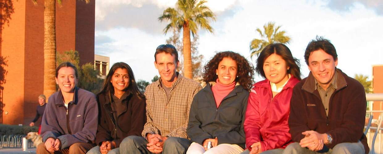 Six people sit on a low wall