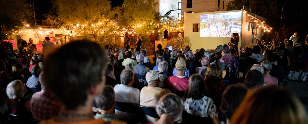 Crowd of people watch a projected video on the side of a building