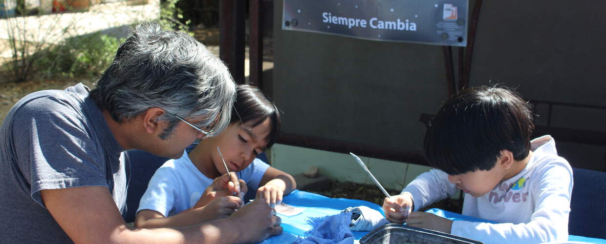 Adult and two kids carving rock art