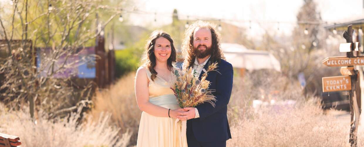 Bride and groom hold bouquet of wildflowers in sunshine