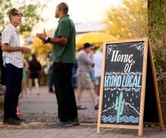 two people chatting at a social event next to a sign saying Home of Hydrolocal