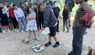 Children participate in an experiment to show how rain basins help with water infiltration