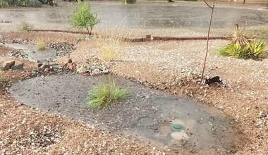 Rain basin with several inches of water during a rain storm. The water is overflowing into a lower basin. 
